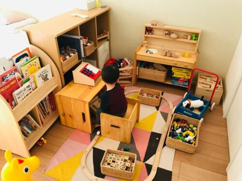 木製レールと木製玩具に囲まれる2歳息子